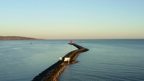 Dolly-Aéreo-En-El-Malecón-De-Dublín-Al-Atardecer,-Faro-Poolbeg-En-Segundo-Plano.