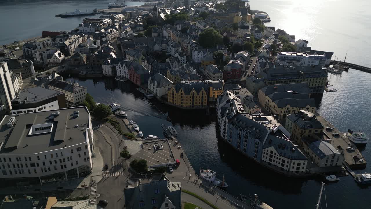 4K drone footage panning sideways close to the colorful Art Nouveau buildings by the waterfront in Ålesund, Norway, capturing reflections on the water under bright summer light