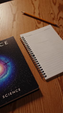 notebook, book, and pencil on wooden table