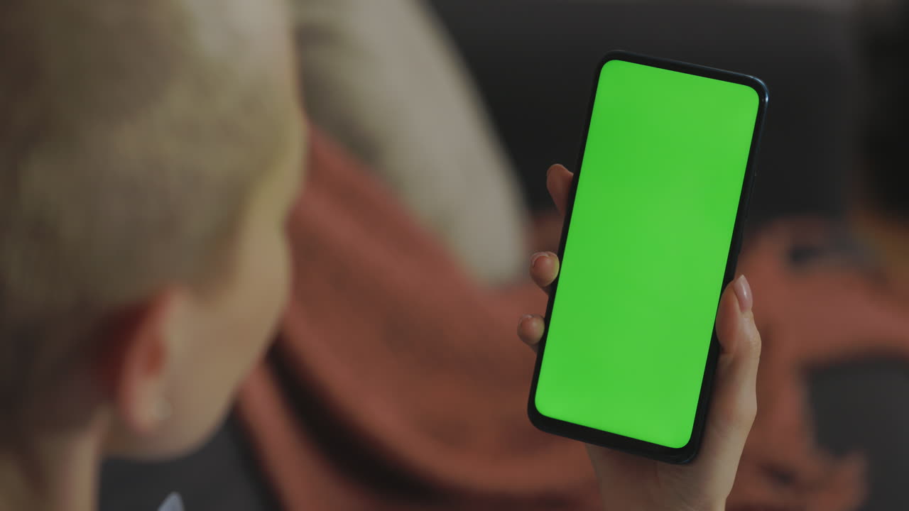 Person holding smartphone with green screen