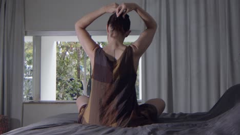 un maniquí se sienta en la cama y levanta su cabello con una pinza para el cabello para su maquillaje