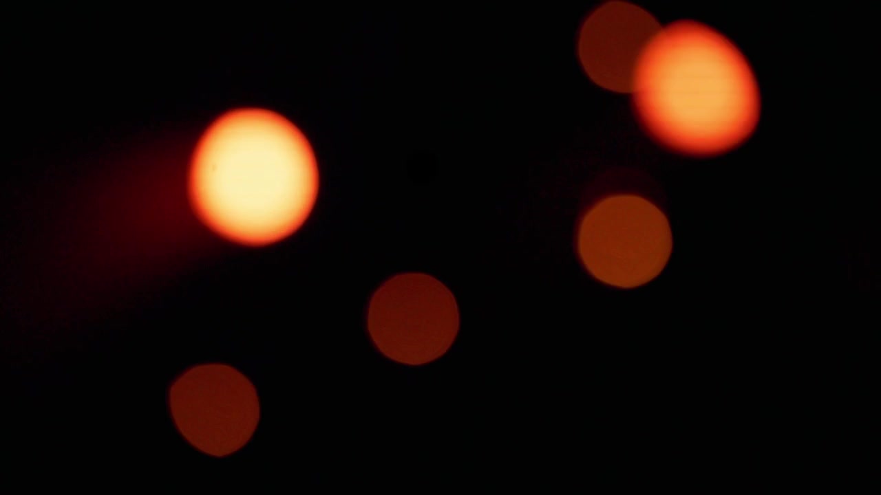 Floating orange bokeh particles in space. Artistic light rays for psychedelic music backgrounds and VJ mixing.
