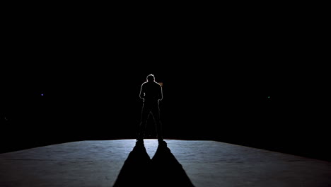 senior man in costume on stage in darkness. active man in hat dancing on stage during the performance in the theater.