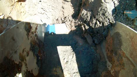 pov, excavator bucket digging soil from underground at construction site