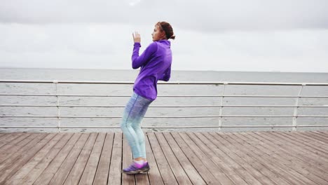 young woman exercising, kicking legs and stretching on the beach by the ocean early in the morning. slow motion shot