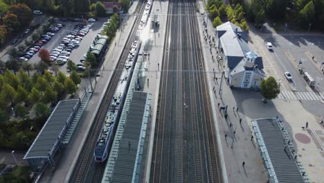 Aerial-tilts-down-to-passengers-waiting-at-Kerava-Railway-Station,-FIN