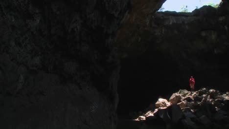 Beautiful-pan-across-a-deep-dark-cave-to-reveal-a-Masai-warrior-standing-in-a-pool-of-light-in-Kenya