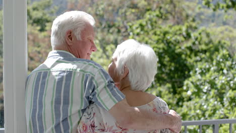 Happy-senior-caucasian-couple-standing-on-balcony-and-embracing,-slow-motion