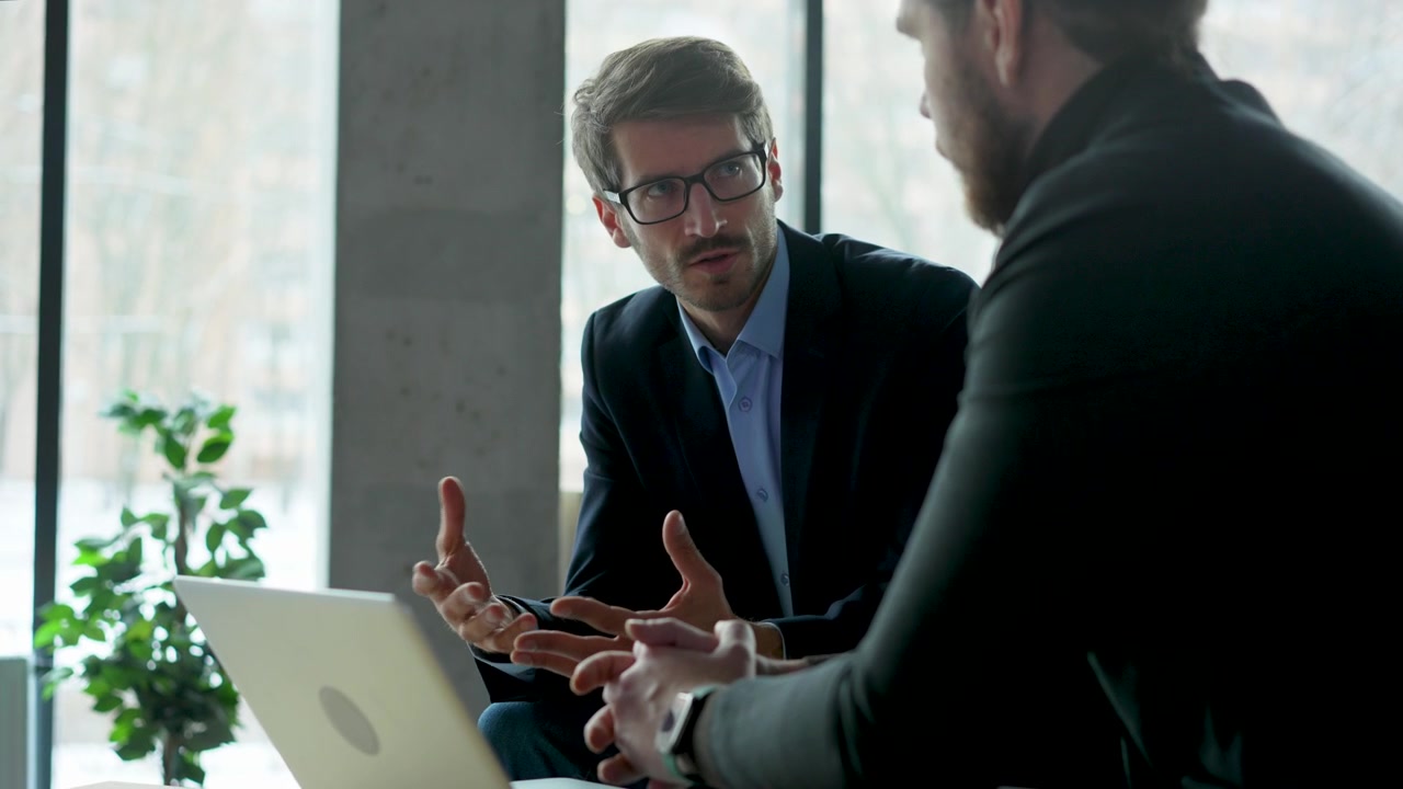 Due uomini d'affari che discutono di strategia in un ufficio moderno.