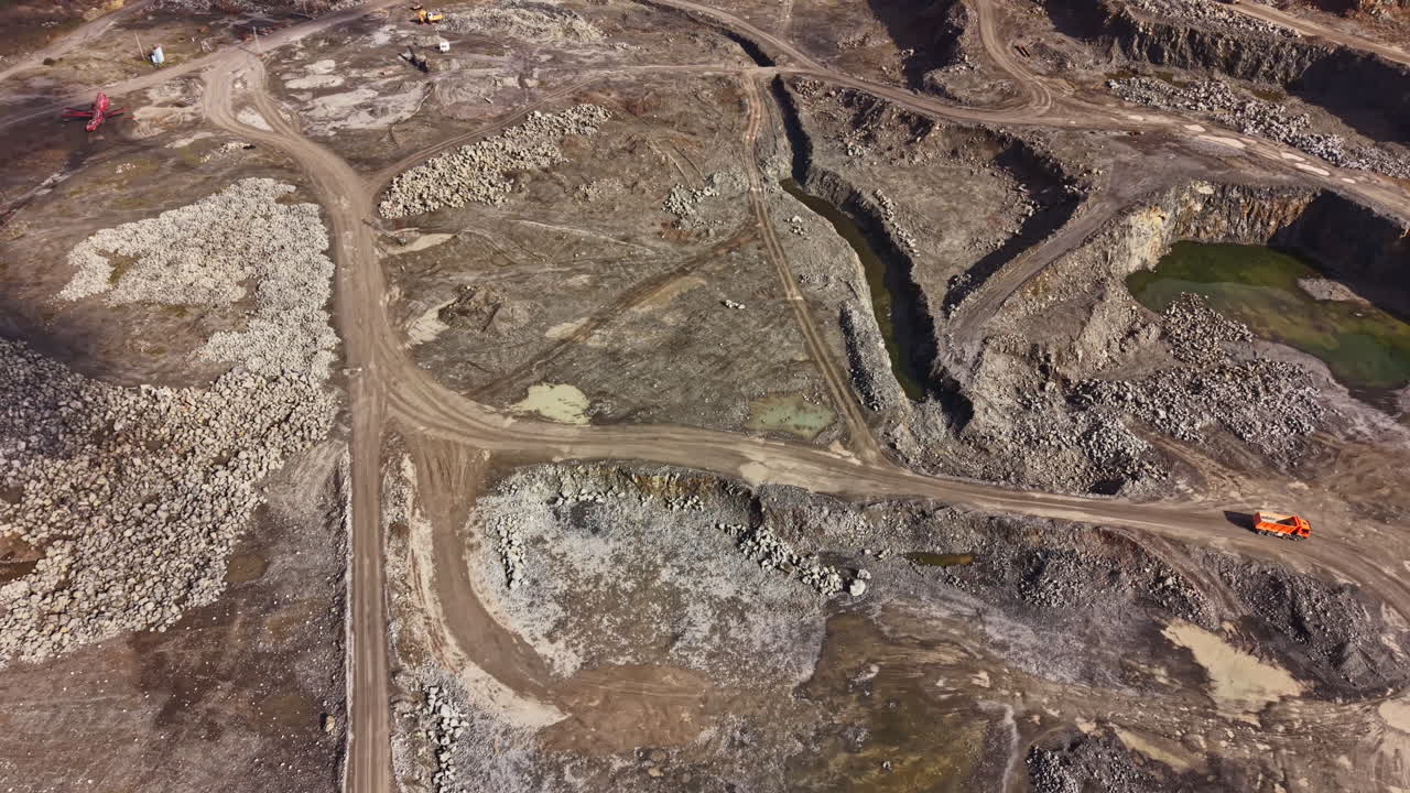 Quarry site shows machinery and raw granite with dirt paths in the landscape during daytime