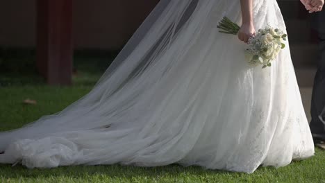 bride walks on grass with flowing white dress and bouquet in hand