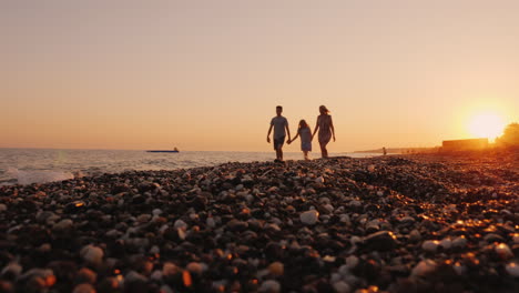Family-With-A-Child-Walking-At-Sunset-At-The-Seashore-Relaxing-Together-At-A-Resort