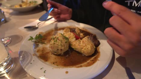 a person slowly cutting carbohydrate rich food on a plate - close up shot