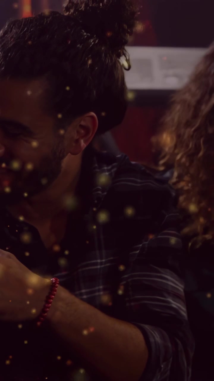 Vertical video: Man leaning, smiling holding bottle, socializing in music studio with gold overlay