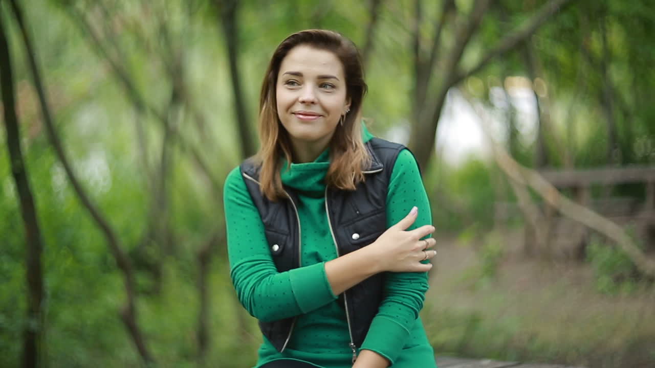 Donna seduta su una panchina nella natura. Giovane donna seduta su una panchina e che sorride al parco