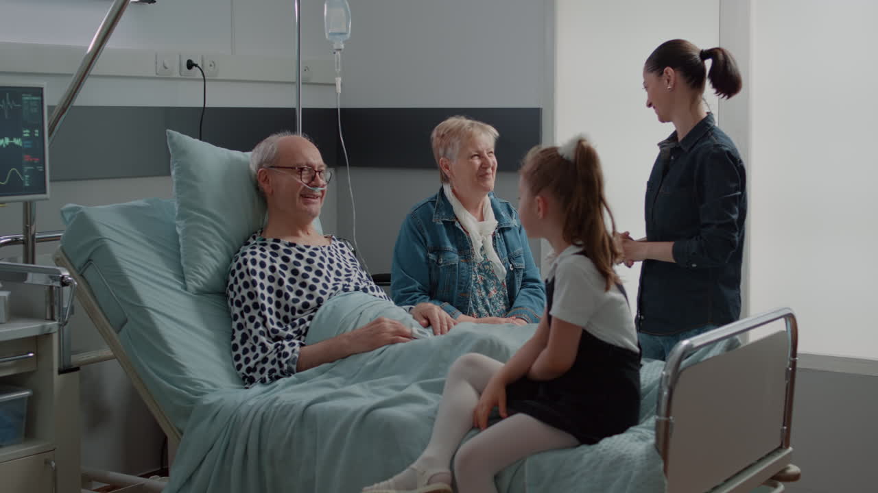 Senior man enjoying chat with niece at visit in hospital ward bed