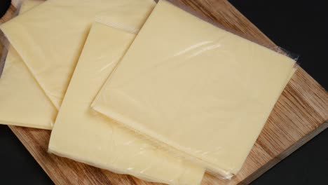 sliced processed cheese on a wooden cutting board