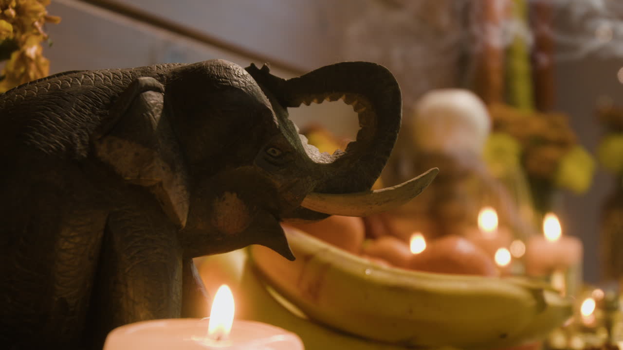 Still life with elephant statue, fruit, and candles