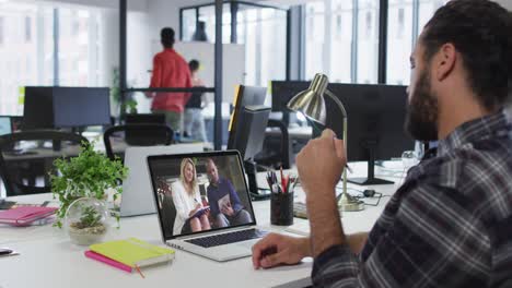 hombre de oriente medio teniendo una videollamada con colegas masculinos y femeninos en una computadora portátil en la oficina