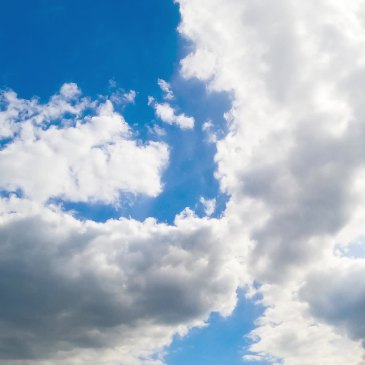 Two big clouds meet in the horizon forming one. Sky being covered with cloudscape. View from below. Timelapse
