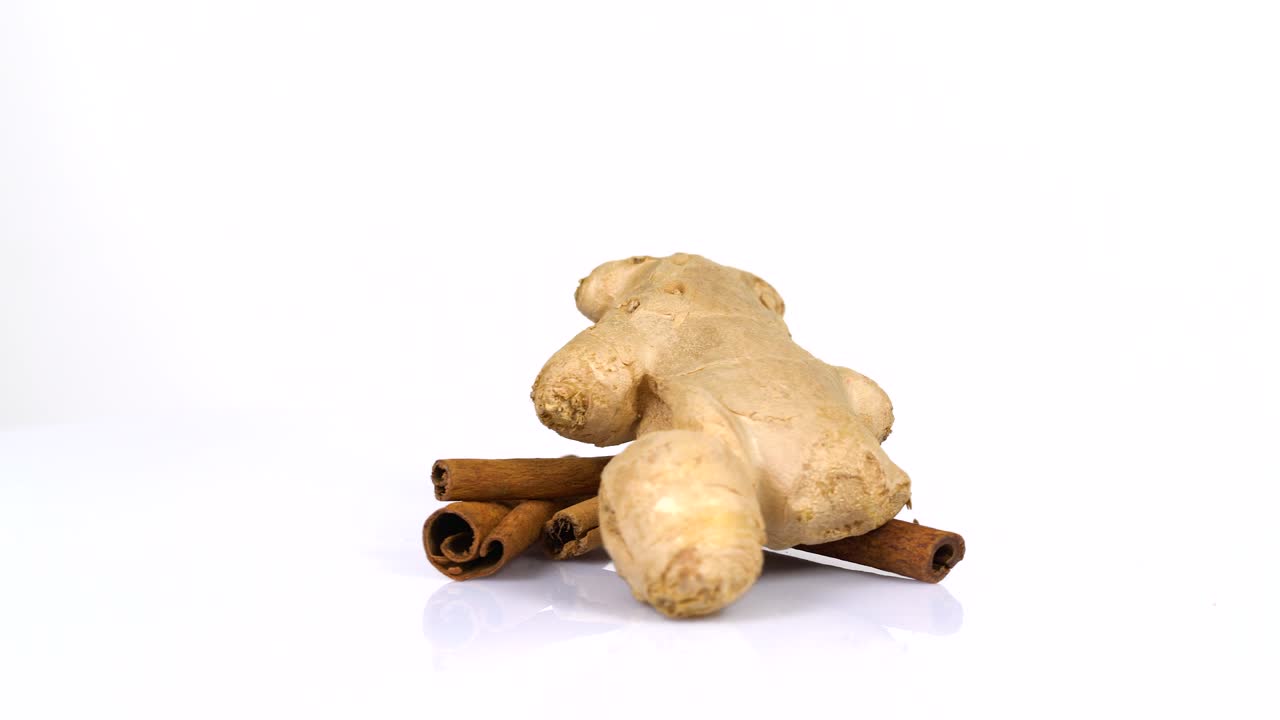 un bucle interminable de palos de canela frescos y jengibre girando sobre un fondo blanco. vista lateral.