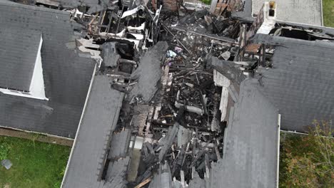 burned rooftop of private estate, ashes and black wood, aerial top down descend view