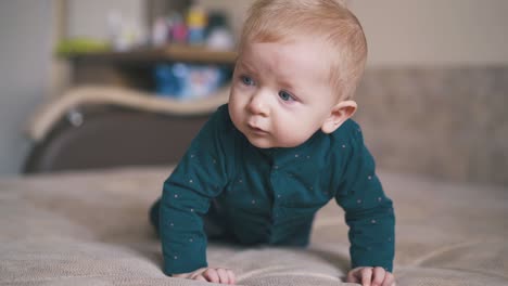 Un-Niño-Con-Ojos-Azules-Brillantes-Aprende-A-Gatear-En-La-Cama.