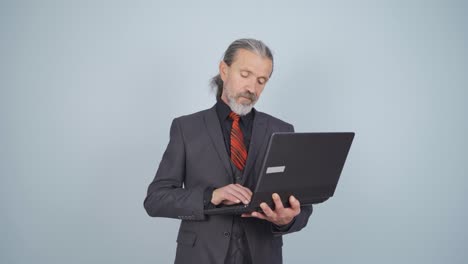 hombre de negocios mirando la computadora portátil con expresión cansada.