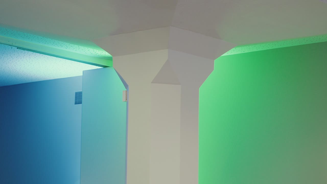 Angolo interno moderno e astratto con illuminazione LED blu e verde tenue che crea un'atmosfera rilassante, design architettonico futuristico e geometria delle pareti minimalista.