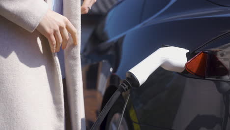 mujer cargando un coche eléctrico