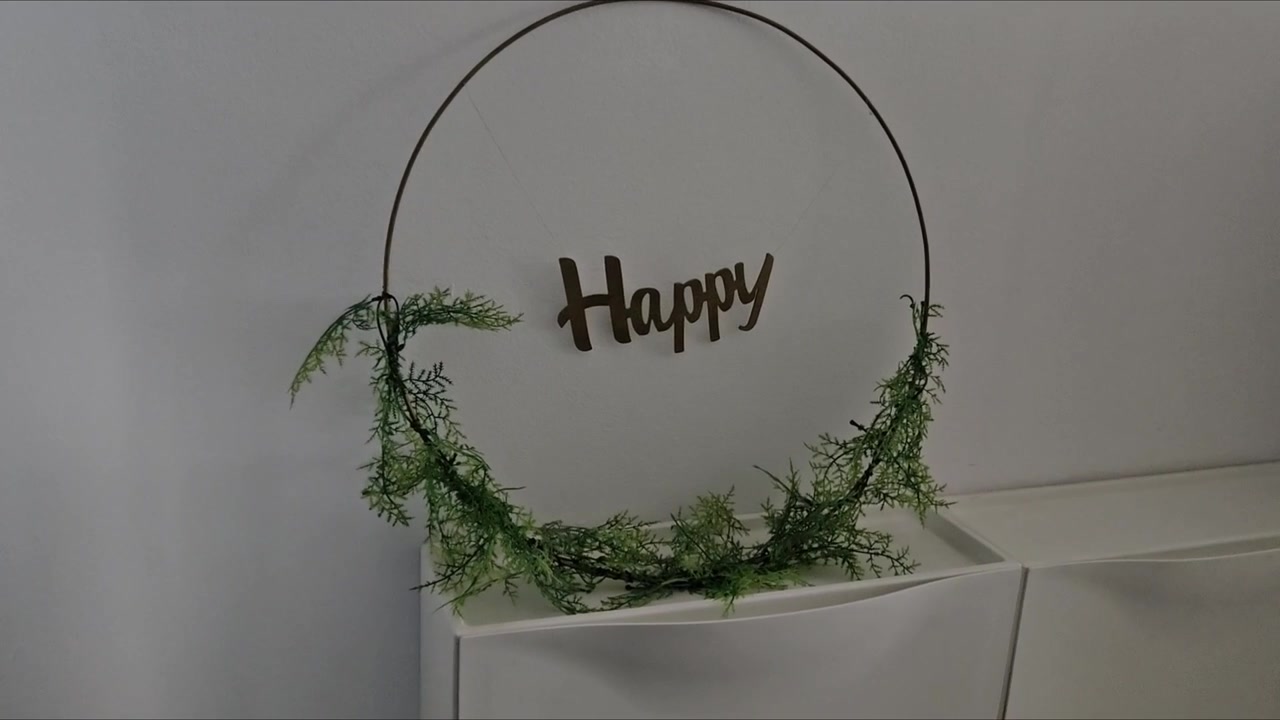 Kreativ blomsterramme med en metallring og et 'Happy'-skilt. Elegant grønt rammedesign perfekt for bryllupsbakgrunn eller festdekorasjon.