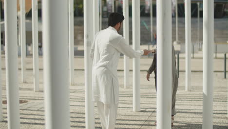 happy young muslim couple dancing between columns on sunny day.