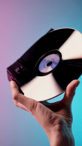 a hand interacting with an optical disc and inserting it into a device