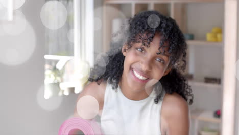 animation of light spots over portrait of happy biracial teenage girl smiling at home