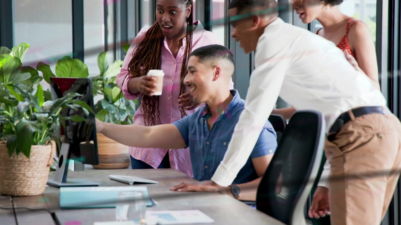 Seated man pointing at monitor after colleague leaning over, office team reviewing work on screen