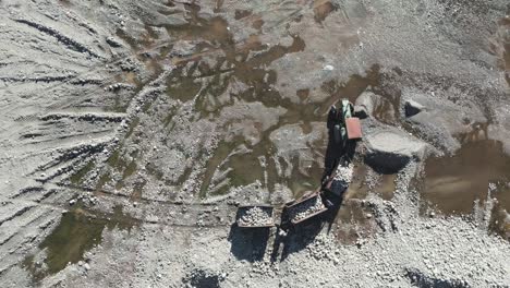 tractor con tres remolques de basura quitando piedras de un lecho de río seco en el verano de las montañas de los andes