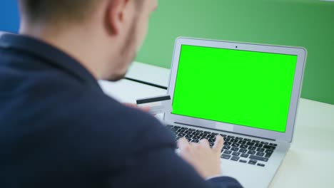 a young man using a laptop with a green screen