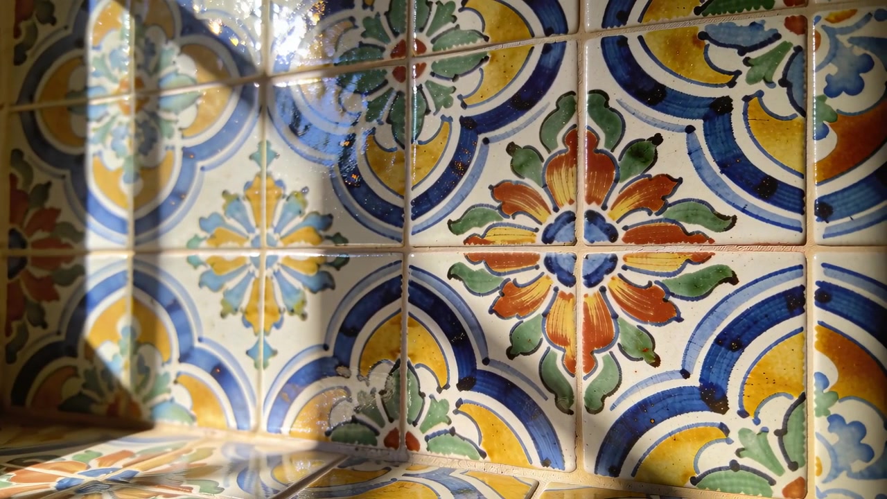 La luce solare che cambia rivela piastrelle di ceramica smaltata in una nicchia interna, esponendo la malta e il riverbero.