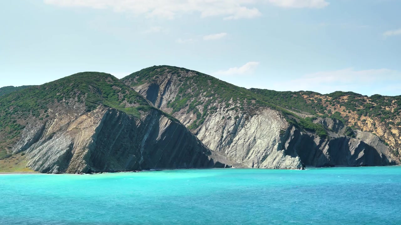 Onde turchesi dell'oceano che si infrangono contro aspre scogliere costiere