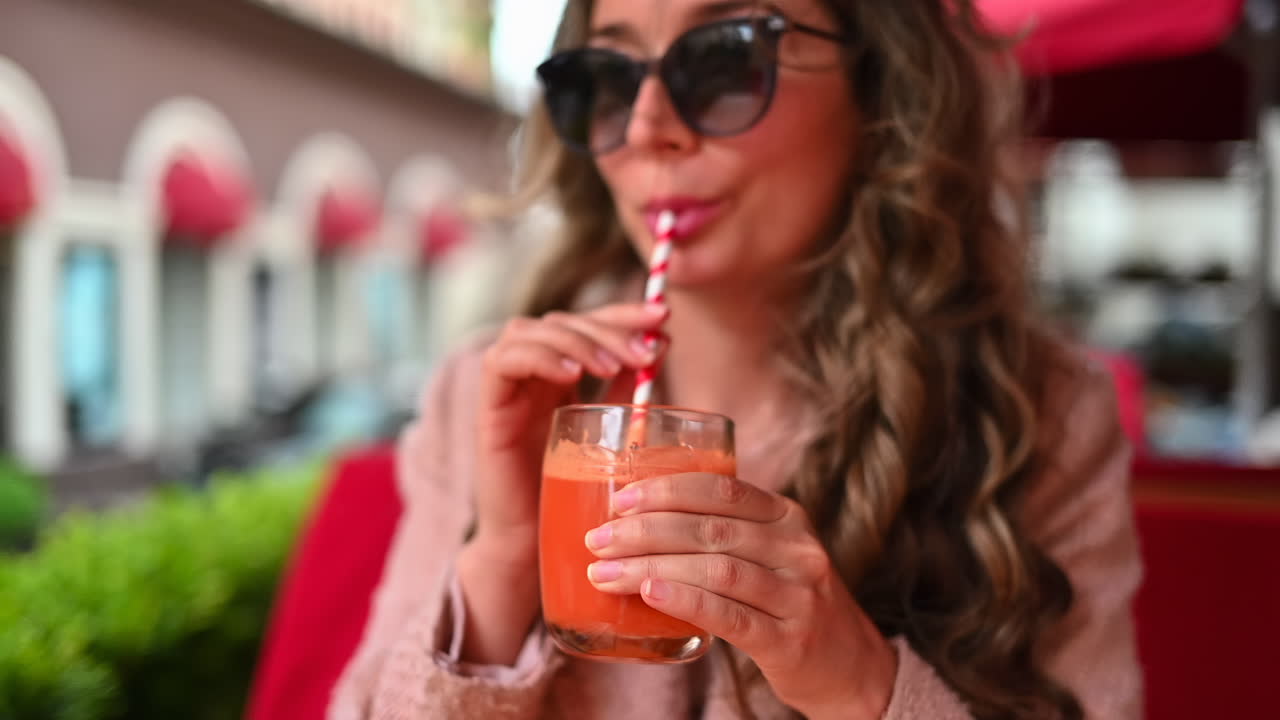 Woman drinking fresh carrot juice at a restaurant terrace