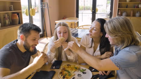 grupo de cuatro amigos felices compartiendo pizza y divirtiéndose en el restaurante 1