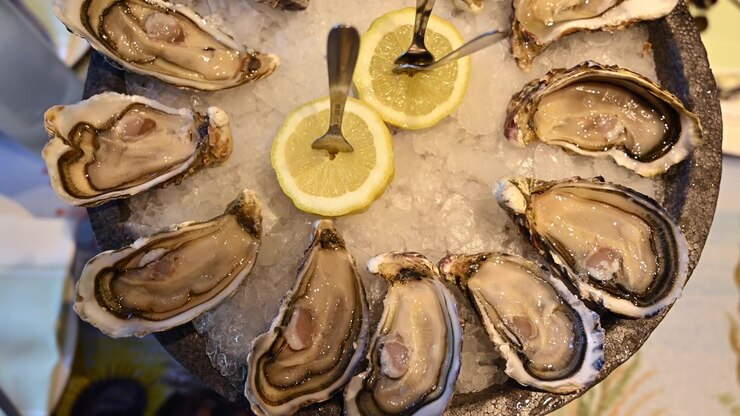 Fresh oysters displayed on crushed ice with sliced lemons in a seafood restaurant setting