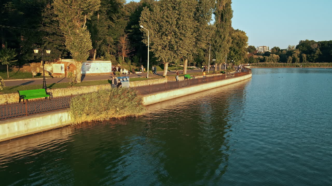 Aerial drone view of Valea Morilor park at sunset. Lush greenery, lake, walking and resting people
