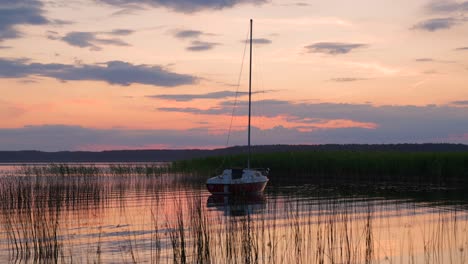 a sailboat anchored in a picturesque river bay during sunset