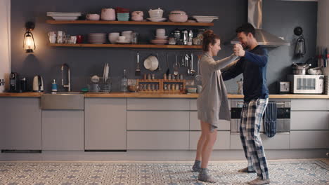 happy young couple newly wed dancing listening to music in kitchen wearing pajamas coffee morning at home