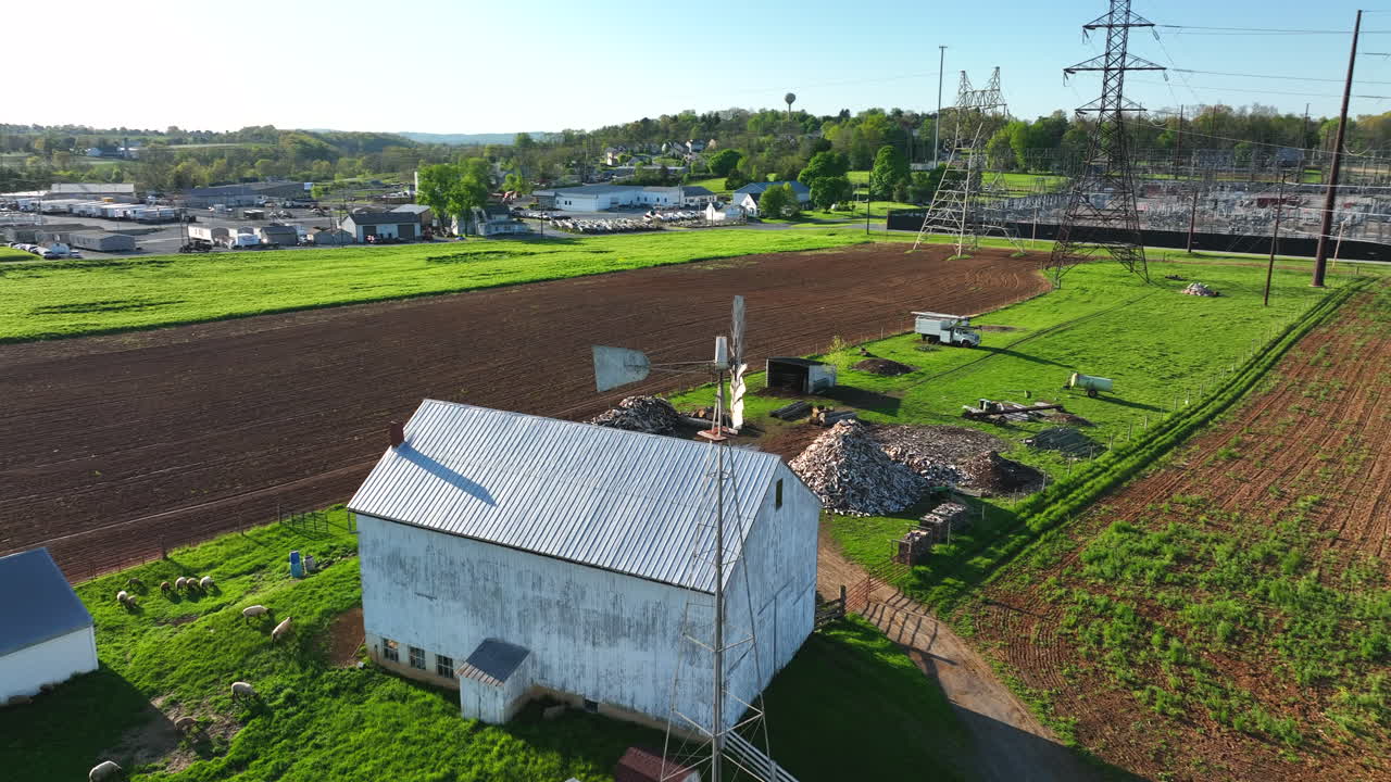 미국 시골의 아미시 농장에 있는 재생 에너지 풍차와 전기용 고압 전선의 대조