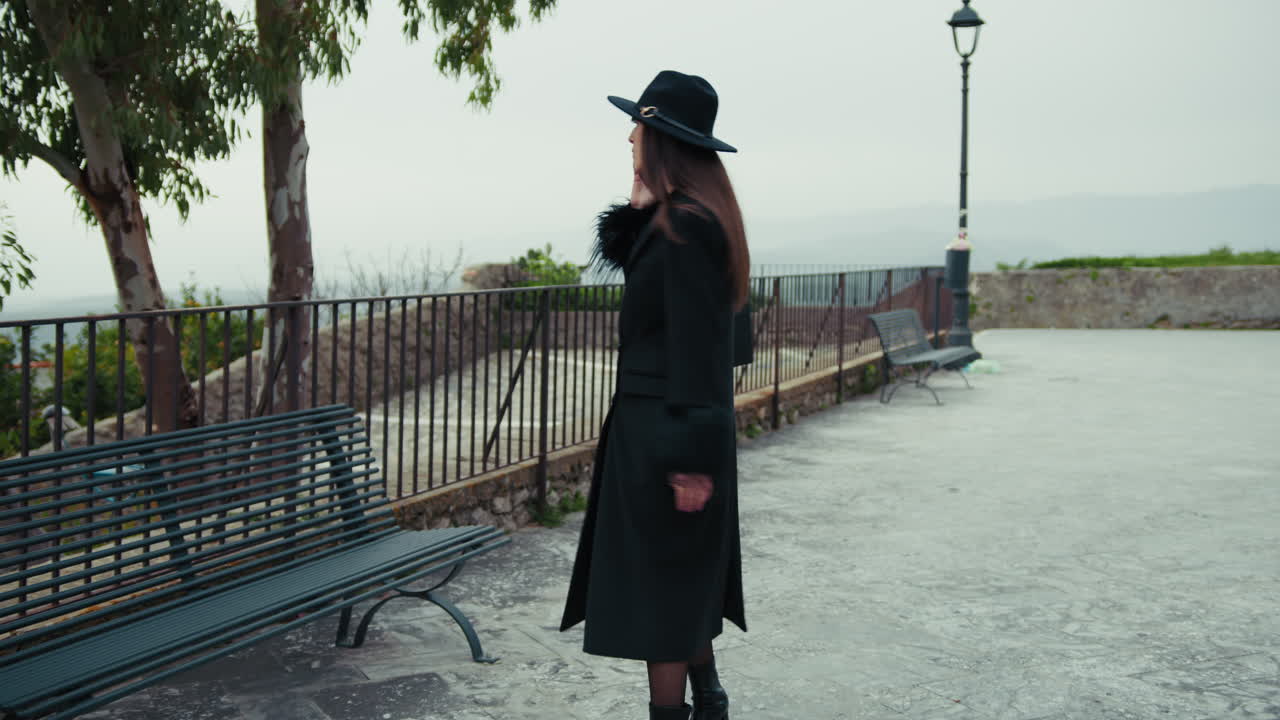 Elegant Woman In Total Black Walking With The Phone In The Town Park