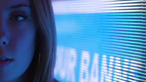 half-face portrait of young woman against a neon led sign