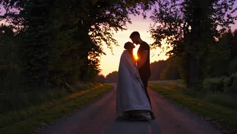 a romantic couple sharing intimate moments on a tree-lined path at sunset