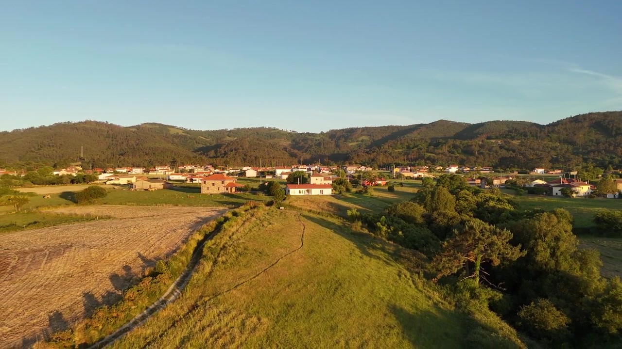 Vista con drone all'ora d'oro di un villaggio rurale delle Asturie circondato da campi